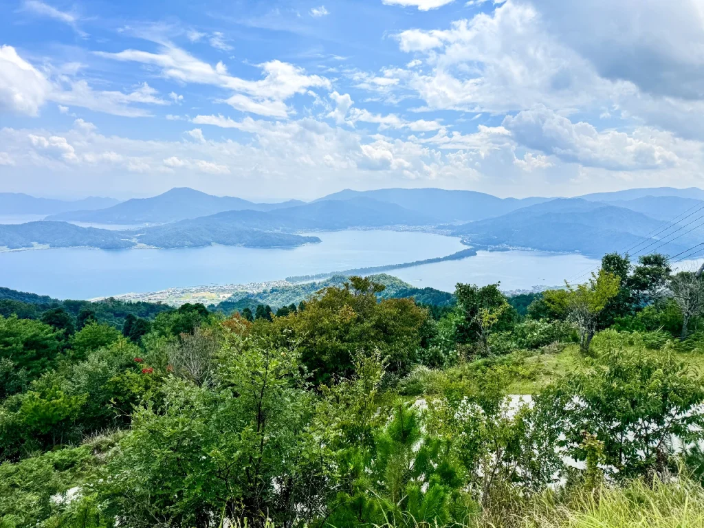 成相寺敷地内の山頂展望台から天橋立を一望した写真です。海に一筋の緑の線が走っています。