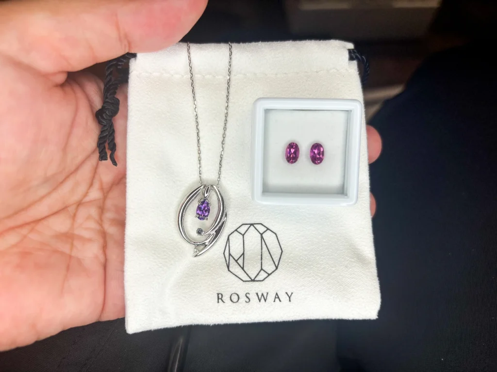 ROSWAYさんでオーダーしたアメシストのネックレスとマラウィのマゼンタガーネット。 白く小さなROSWAYさんの巾着の上に載せて撮りました