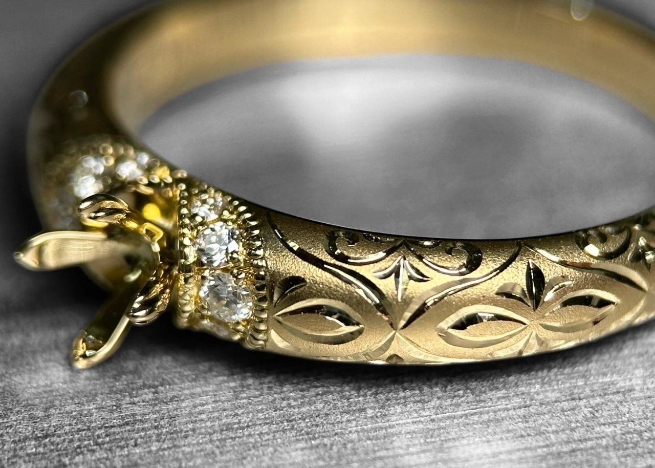 LARICHのKAZANEリングの画像です。グレーの台に石座をこちらに向けたKAZANEリングが横たわっています。